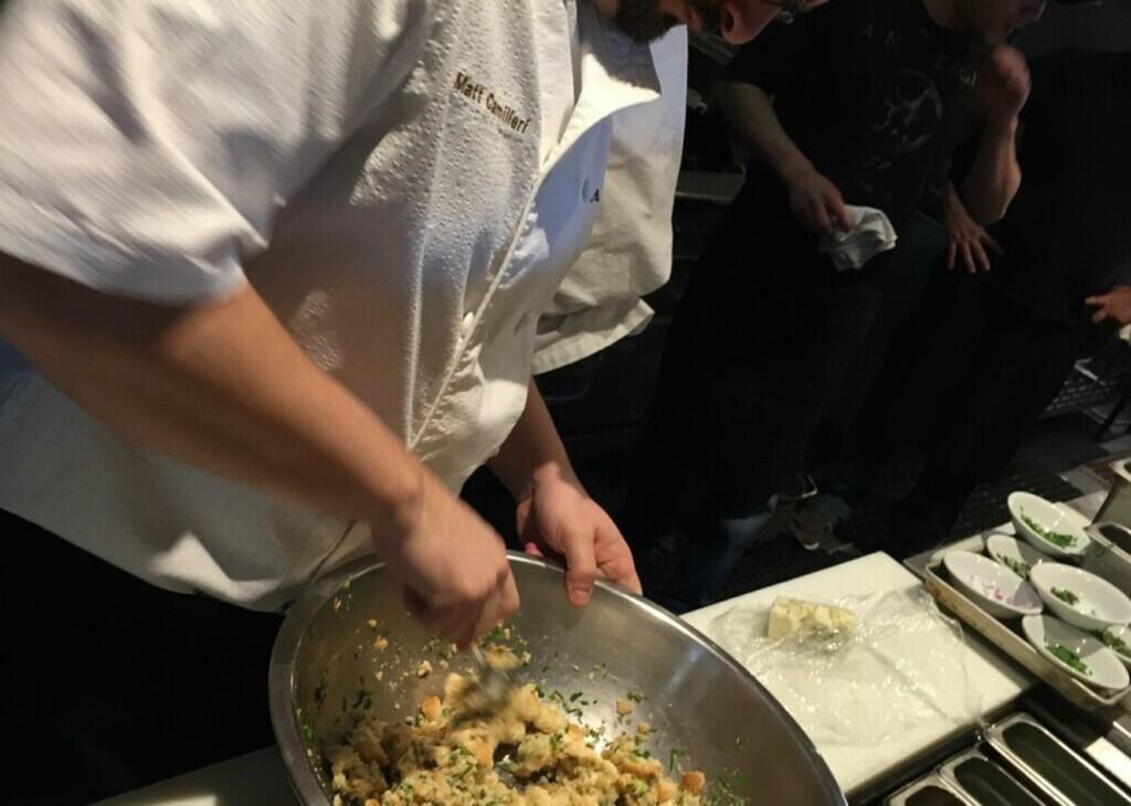 chef stirring ingredients in a metal bowl